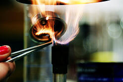 Person lighting a bunsen burner in a lab. 