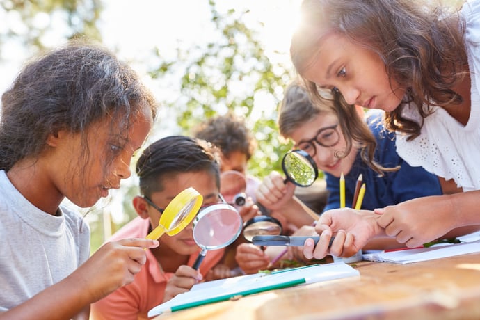 Student observing something closely with magnifying glasses